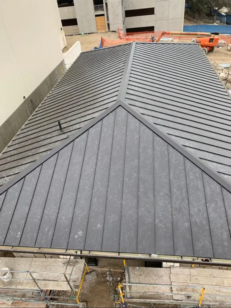 Commercial metal roof construction with crane equipment in Astoria